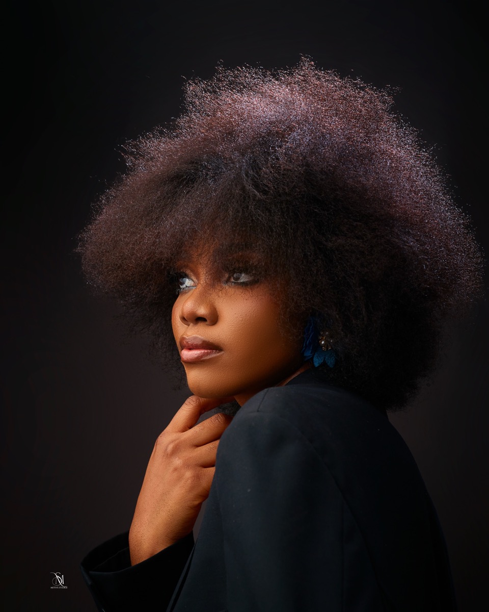 Close studio portrait with afro hair against a dark backdrop